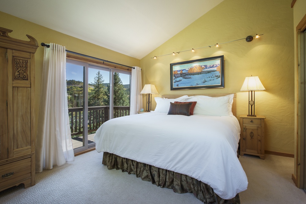 View into the Master bedroom with king-size bed, large armoir, closet, private balcony, and en-suite bathroom.
