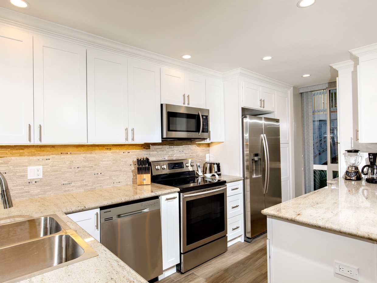 The remodeled kitchen features granite counters, stone back splash, stainless appliances, and a wood-look porcelain floor.
