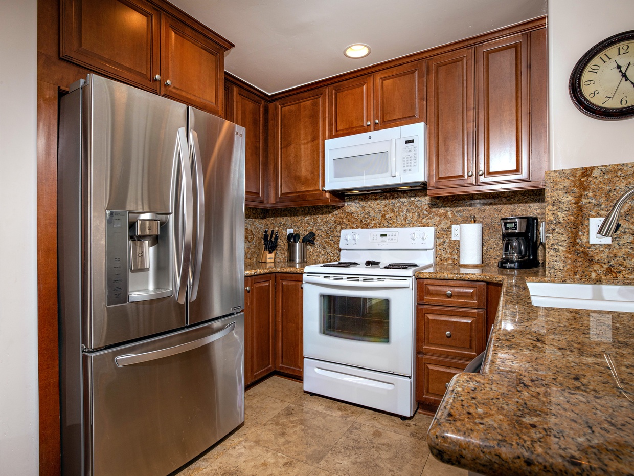 The kitchen features slab granite countertops and rich wood cabiniets.