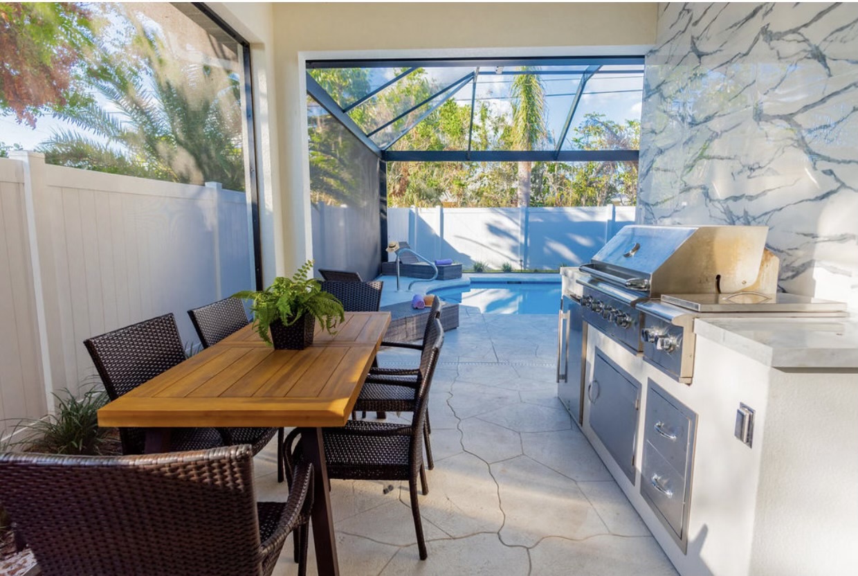Newly renovated outdoor kitchen with custom marble backsplash and spacious dining table.