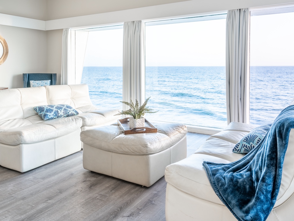 Coastal living room with white leather sofas and sweeping ocean