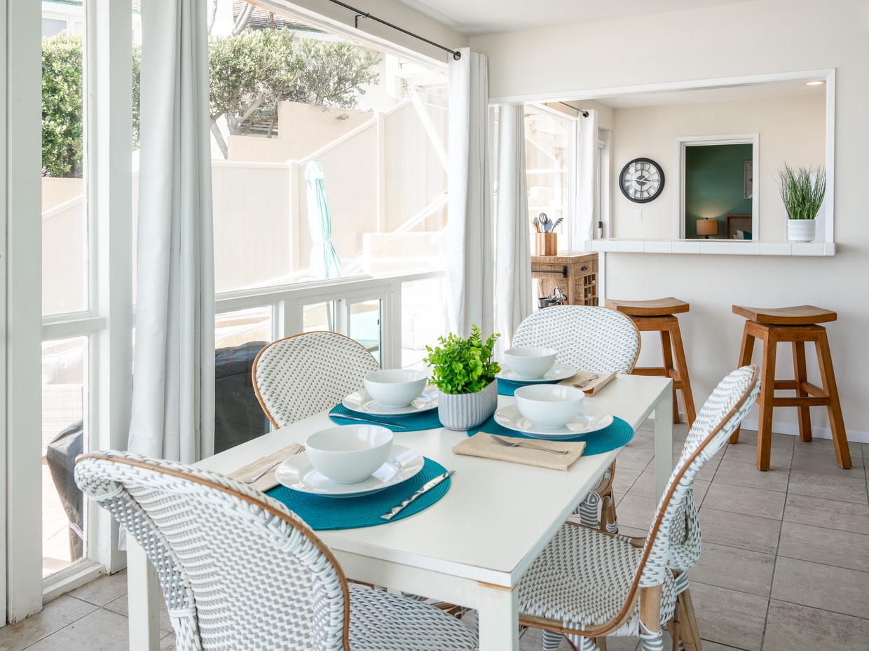 Bright dining area with white wicker chairs and large windows ov