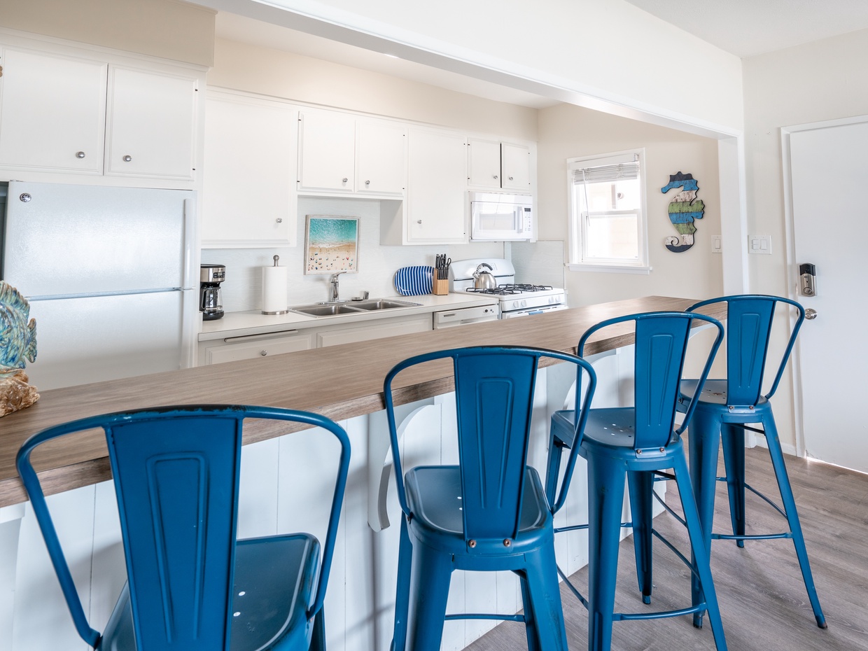 Bright kitchen with white cabinetry, breakfast bar, and blue met