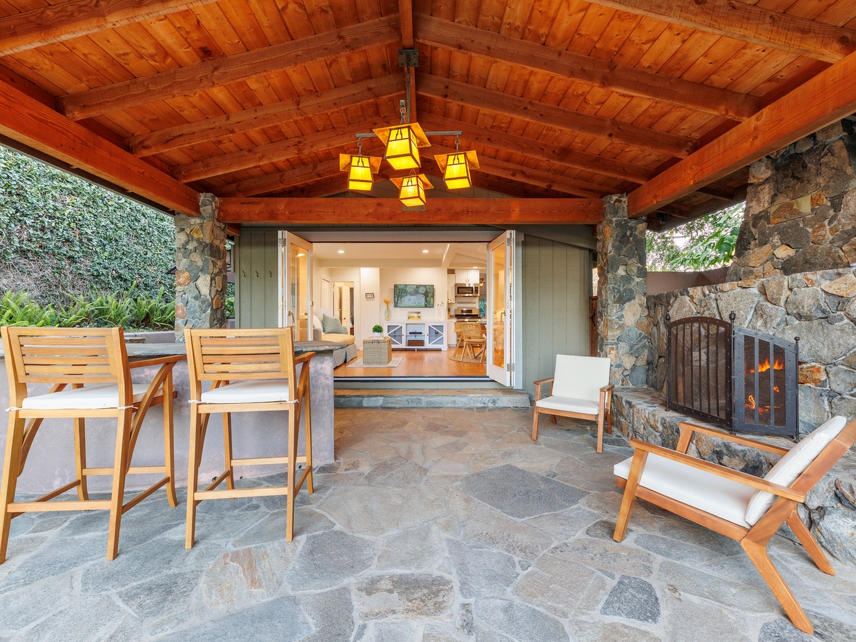 Covered outdoor patio with wooden ceiling, stone fireplace, bar 