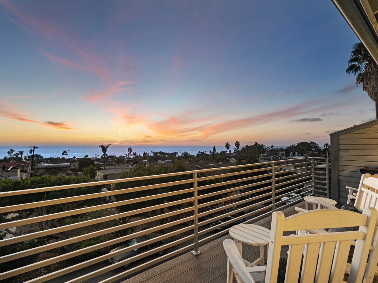 Sunset ocean view from an elevated balcony with Adirondack chair