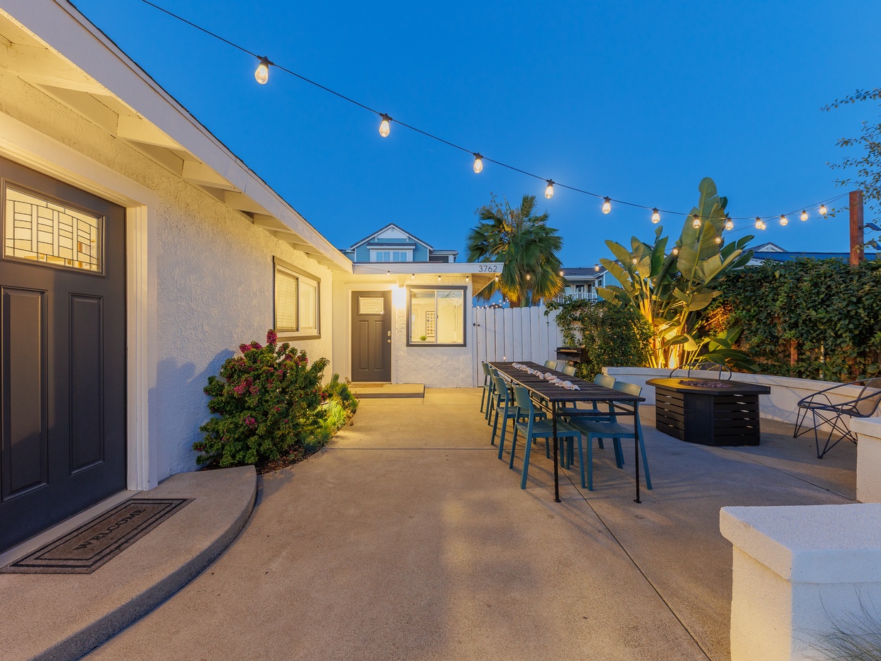 Evening patio with outdoor dining table, firepit, and tropical l