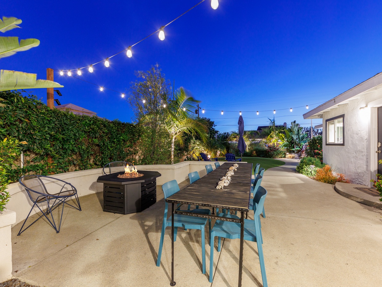 Backyard patio with firepit, outdoor dining table, string lights