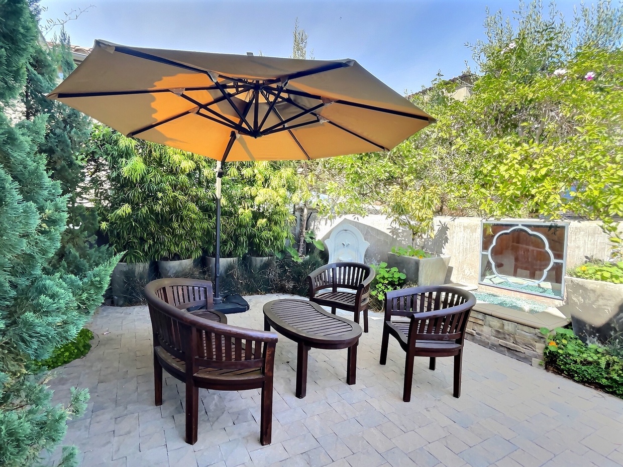 The courtyard entrance offers a shaded retreat with seating near a tranquil water feature.

