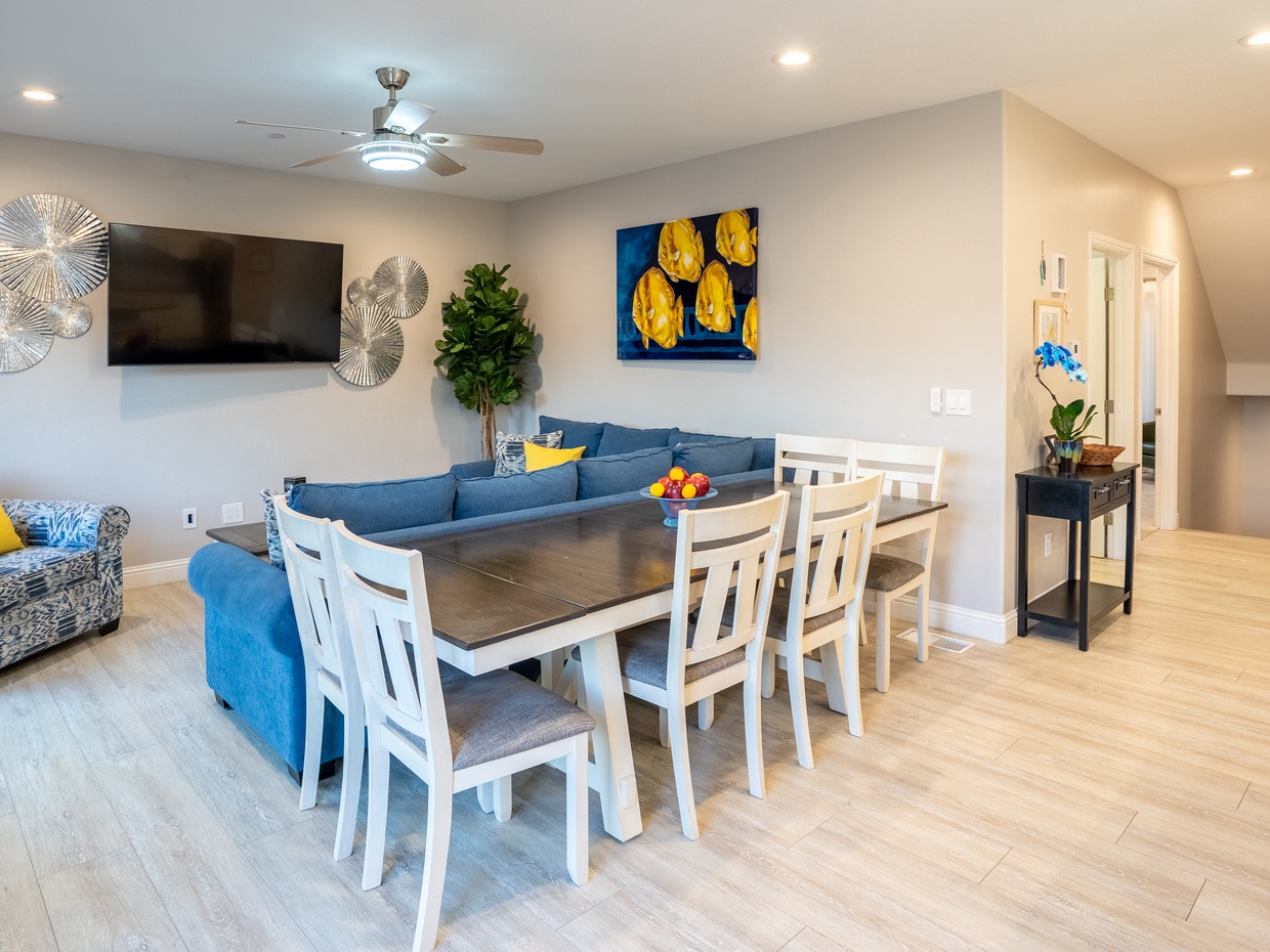 The living room boasts a captivating blue aesthetic and is outfitted with a Smart TV. Ample seating arrangements invite family and friends to gather around the television, while the open layout seamlessly connects to the kitchen, ensuring everyone can enjoy each other's company.

Dining table for 6 guests, plus bar stools at the nearby kitchen island. 