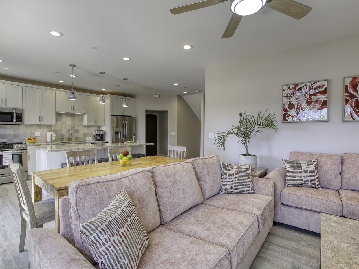 The living room boasts beach-inspired hues of blush and sand and is outfitted with a Smart TV, ready for your Netflix and other favorite entertainment channels. Ample seating arrangements invite family and friends to gather around the television, while the open layout seamlessly connects to the kitchen, ensuring everyone can enjoy each other's company.