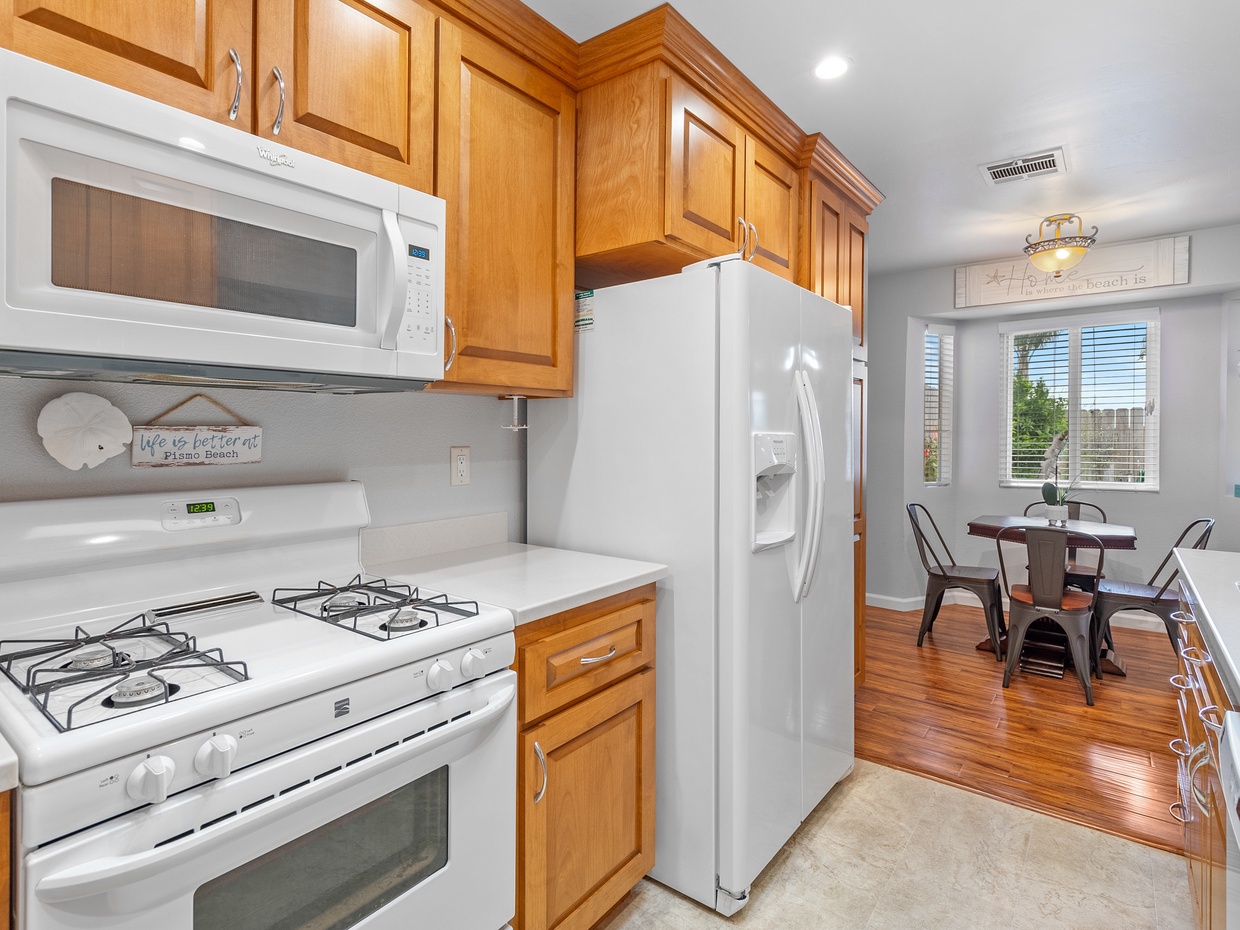 Kitchen with chef grade appliances. The kitchen is stocked with cookware, dinnerware and glasses.