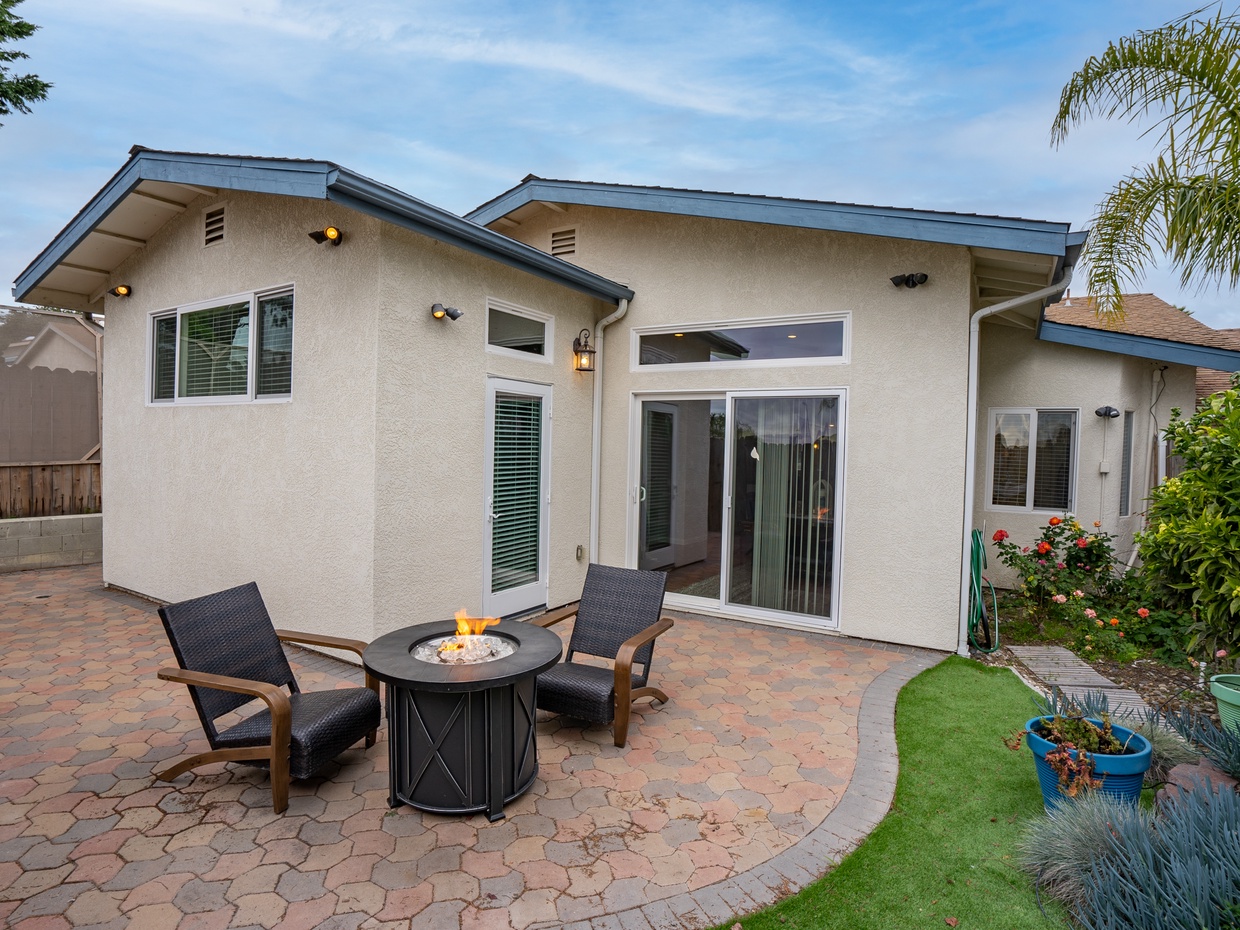 Let's take a peek into the backyard. The backyard is fenced, paved patio, artificial turf lawn and landscaped garden beds. And best yet... a fire table to cozy up for our cooler beach evenings.