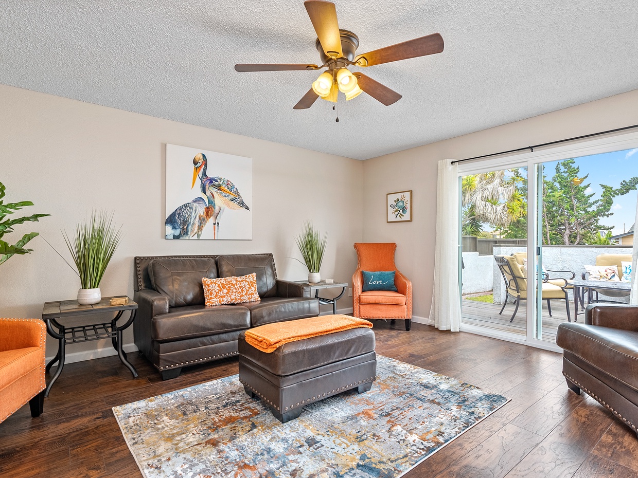 Cheerful living room with an abundance of natural light. Just off the living room is a patio with outdoor furniture and BBQ. 