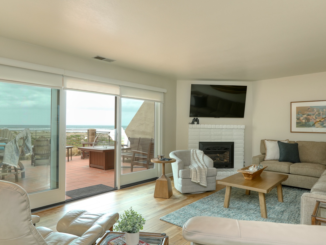 The living room is nestled at sea level, just down a flight of stairs. It features a cozy natural gas fireplace, a SmartTV for all your entertainment needs, and a sectional sofa with a queen pullout for extra guests.