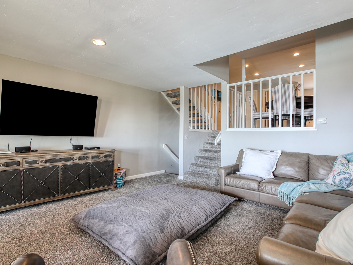 The cozy living room features light, airy décor and ocean breezes through large windows. Relax on the comfy sofa and enjoy the perfect spot for beachy vibes and easy, laid-back living.

