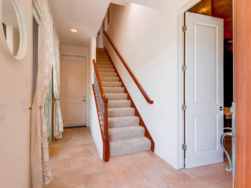 Stairs leading to upper level from front door.  Downstairs bedroom door to the right and laundry to the left.