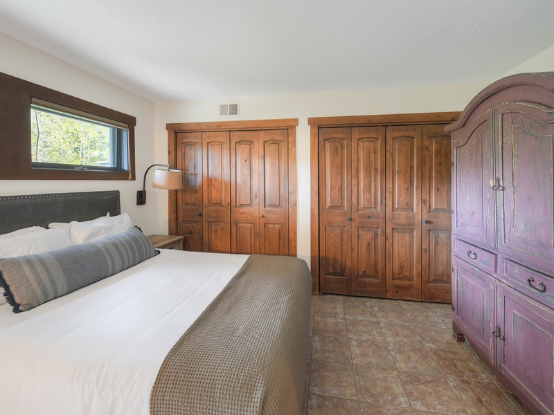 Fifth Bedroom (Level 1): King Bed with writing desk and armoire with a TV inside.