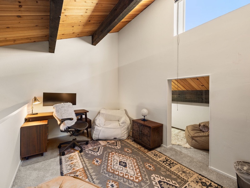 Loft equipped with a desk, desk chair, computer monitor, and comfortable seating