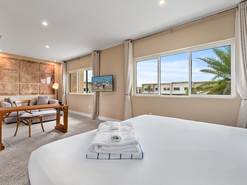 Our master bedroom features a seating area, TV, ensuite bathroom, ample closet space, and a desk to comfortably work or study during your stay.