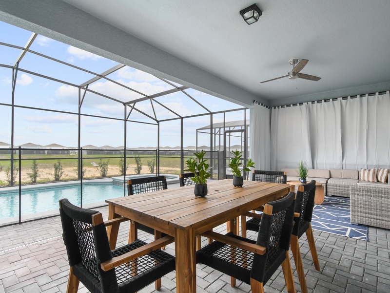 Enjoy a spacious covered patio with cozy seating, and an outdoor dining table, perfect for relaxing or enjoying meals by the pool.