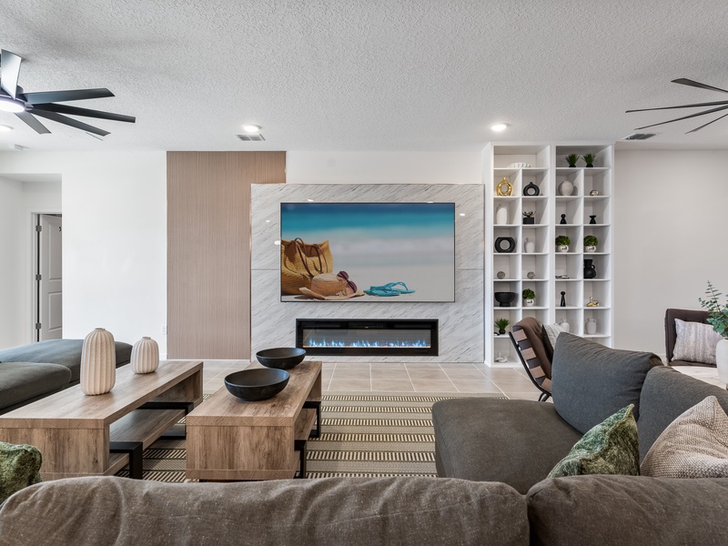 Sleek and spacious living room featuring modern furniture, indoor fireplace, and a large smart TV, perfect for relaxing or hosting a movie night in style.