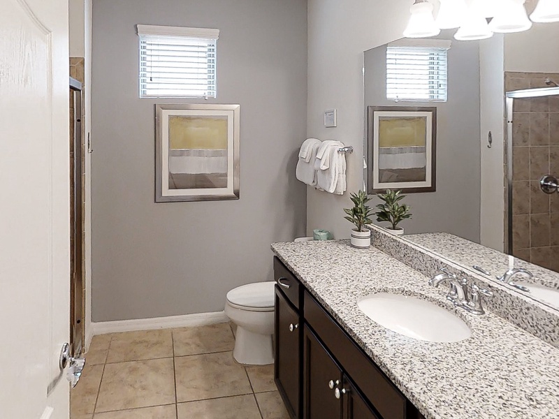 1st floor shared bathroom with single sink extended vanity, walk in shower & toilet.