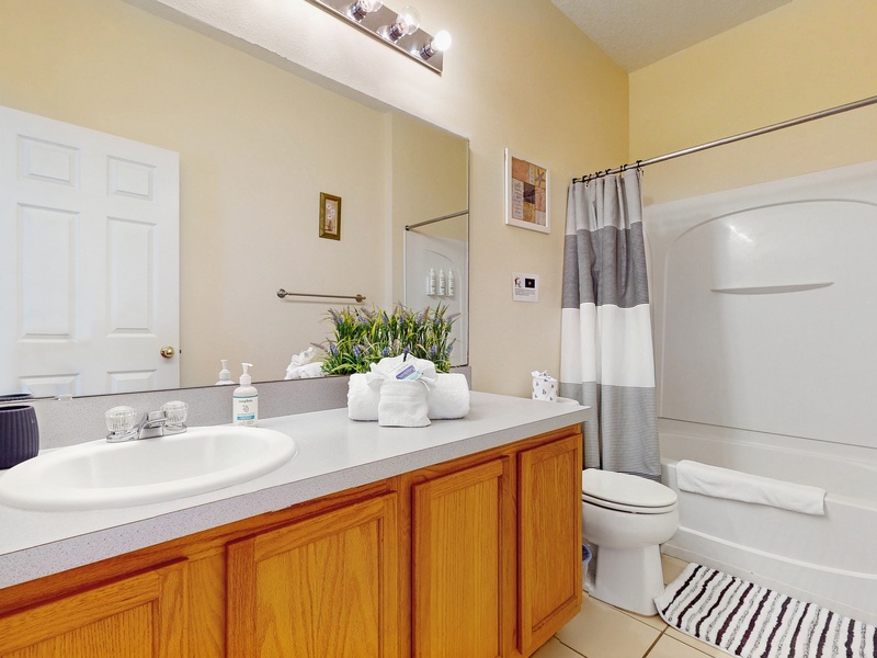 Bedroom #1 private ensuite with single sink extended vanity, shower/tub combo & toilet.