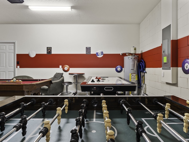The game room features a pool table, air hockey and foosball tables, providing multiple options for an enjoyable game night.
