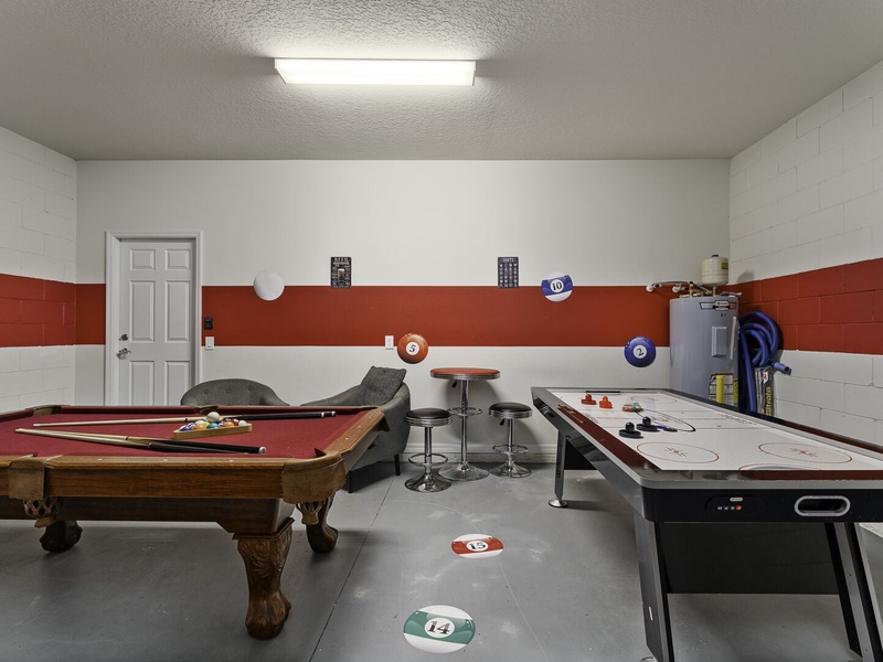 The game room features a pool table, air hockey and foosball tables, providing multiple options for an enjoyable game night.