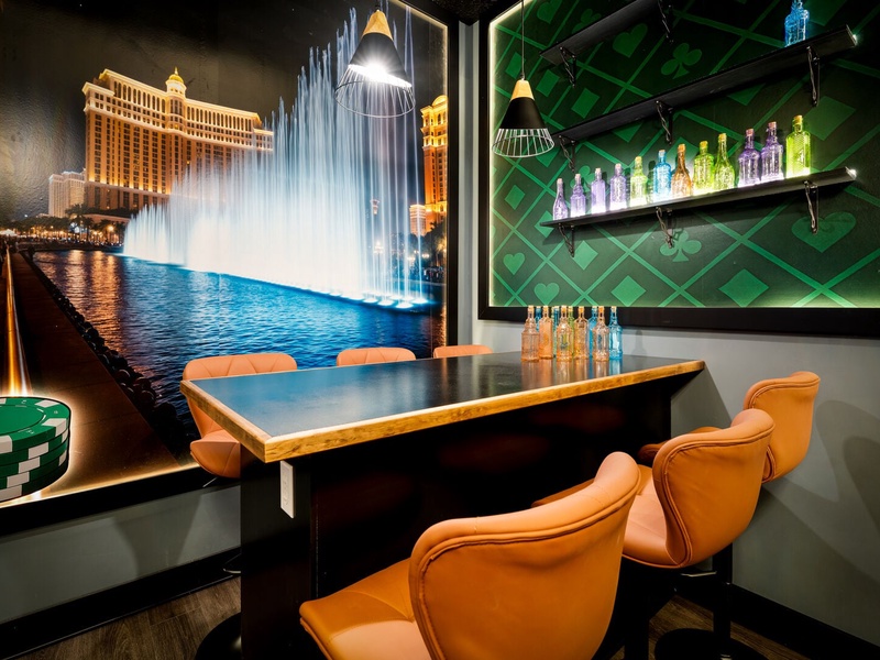 A one-of-a-kind Vegas-style game room featuring a pool table, bar seating, PS5 gaming stations, arcade stations and stunning floor-to-ceiling casino artwork.