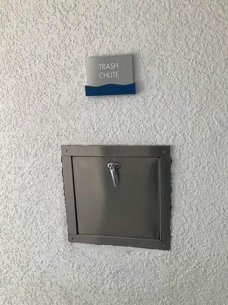 The trash chute is located 30 feet directly in front of the elevator on the same floor.
