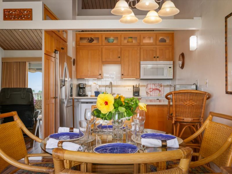 Enjoy meals in this inviting dining space featuring a glass-top table, rattan seating, and bright island accents. The open layout connects seamlessly to the kitchen