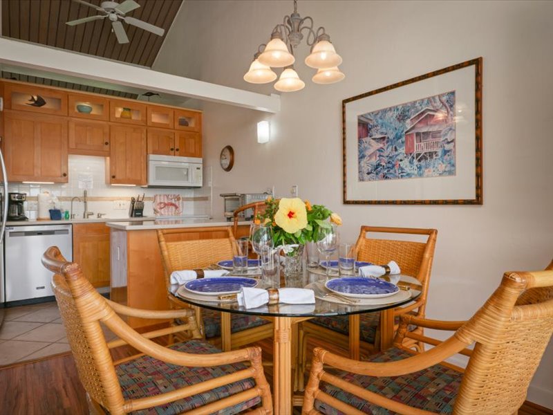 Enjoy casual island dining in this inviting space featuring a glass-top table, rattan chairs, and warm lighting