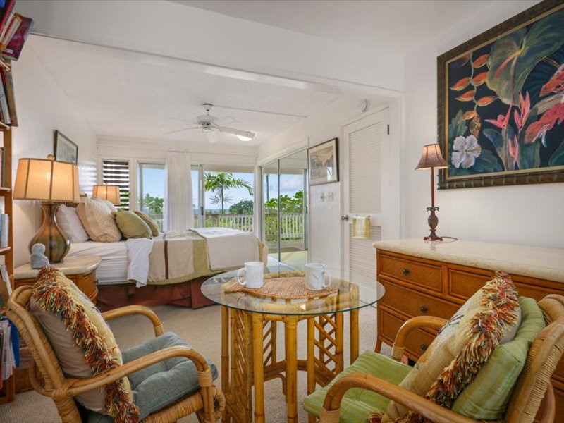 This beautiful primary suite offers a relaxing retreat with a cozy sitting area, tropical-inspired décor, and direct access to a private lanai