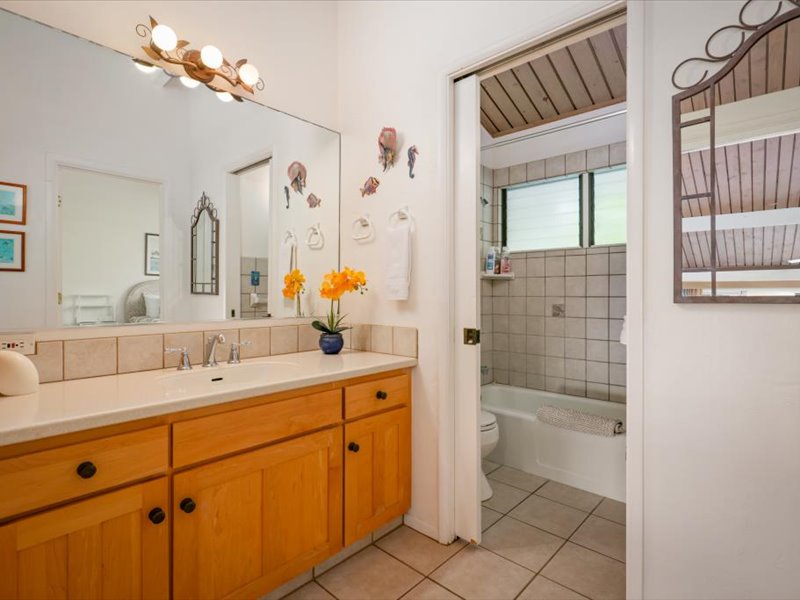 This spacious guest bathroom features a large vanity with plenty of counter space and a full tub-shower combination surrounded by classic tile
