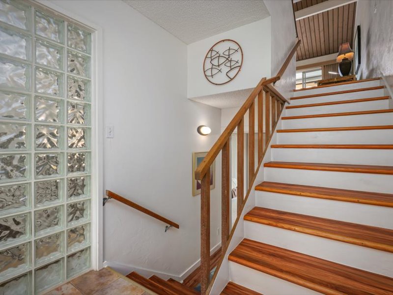 This welcoming entry stairway features beautiful hardwood steps and modern glass block windows that fill the space with soft natural light