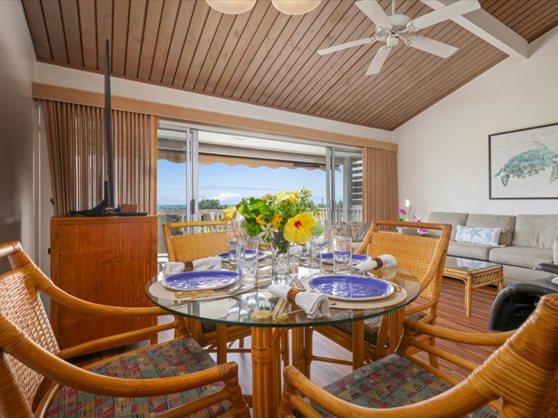 Enjoy meals with a view in this bright, open dining area featuring rattan seating, tropical décor, and large sliding doors that frame the ocean beyond