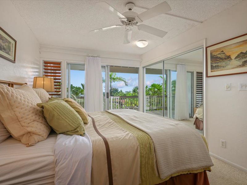 Wake up to soft natural light and tropical views from this inviting primary bedroom