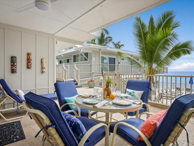 Beautiful ocean-view lanai with cushioned seating and tropical décor, ideal for outdoor dining and relaxation on the Kona Coast.