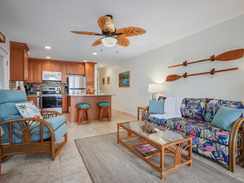 Open-concept living area with tropical furnishings, a full kitchen, and comfortable seating—perfect for relaxing after a day on teh Kona Coast