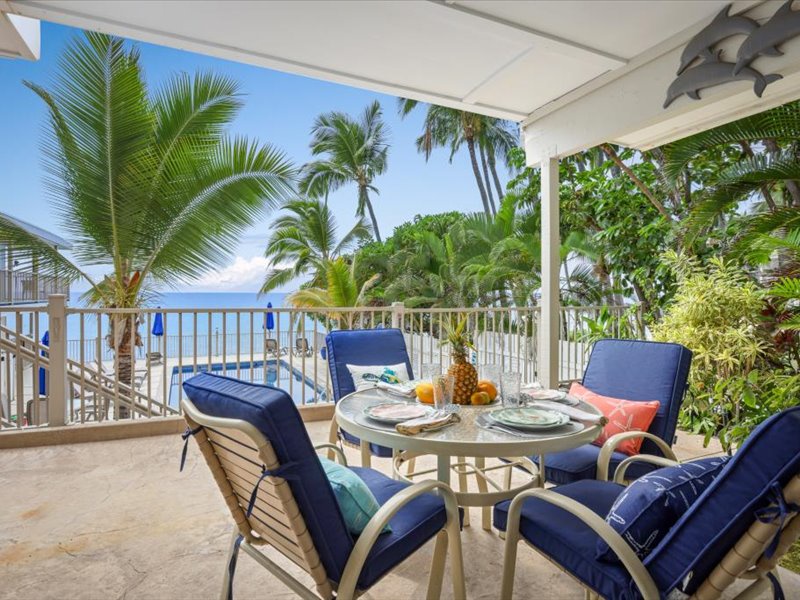 Scenic oceanfront lanai with comfortable seating, perfect for outdoor dining and enjoying breathtaking Kona Coast views.