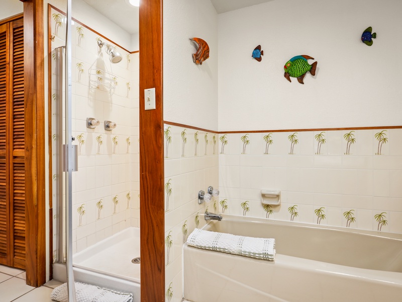Refresh and unwind in this cheerful primary bathroom featuring a walk-in shower, separate tub, and whimsical palm tree tiles—perfect for a relaxing island stay