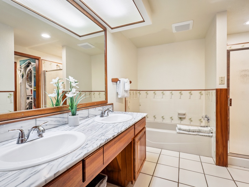 Enjoy the convenience of dual sinks, a full tub, walk in shower, and cheerful palm-accented tile in this roomy bathroom—perfect for couples or families sharing the space