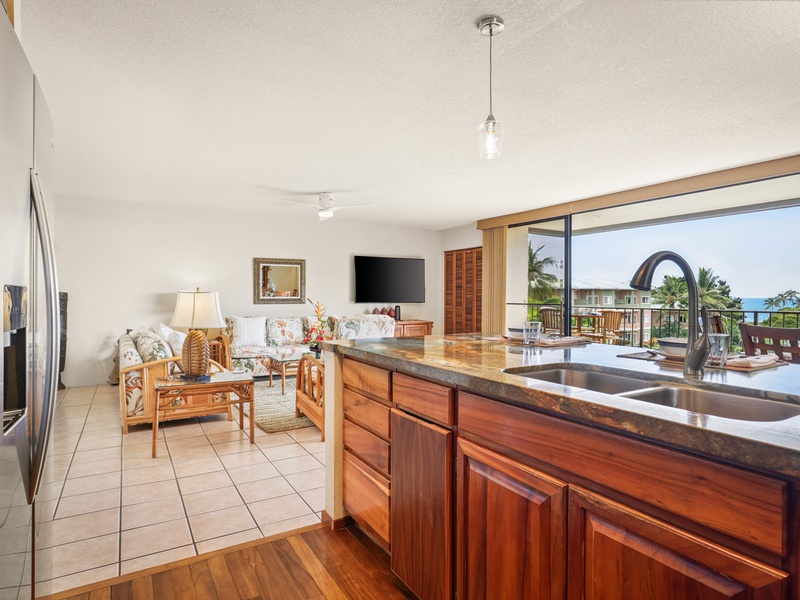 Enjoy stunning ocean views while preparing meals in this open-concept kitchen, featuring rich wood cabinetry and bar seating. The breezy living area and lanai invite you to relax in true island style