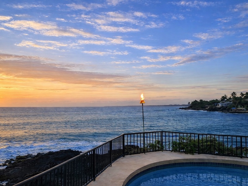 As the sun sets over the Pacific, the oceanfront pool area comes alive with soft evening light and the gentle glow of a tiki torch. Waves roll in against the lava shoreline while the sky shifts to warm golds and blues, creating a peaceful and unforgettable Kona Coast setting. This is the perfect spot to unwind at the end of the day, enjoy sunset views, and experience the true spirit of Hawai?i.