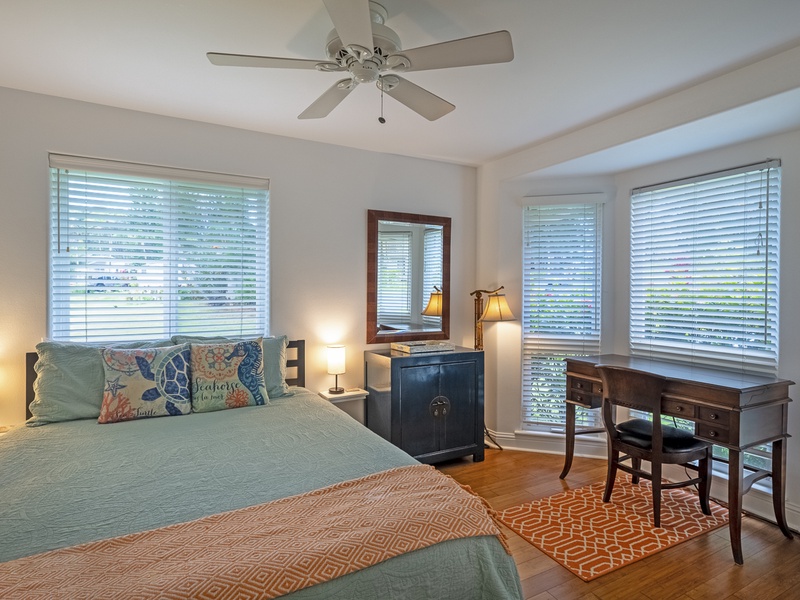 The upstairs guest bedroom is a cheerful and cozy retreat, complete with a queen size bed and writing desk for getting ready or setting up your remote office!