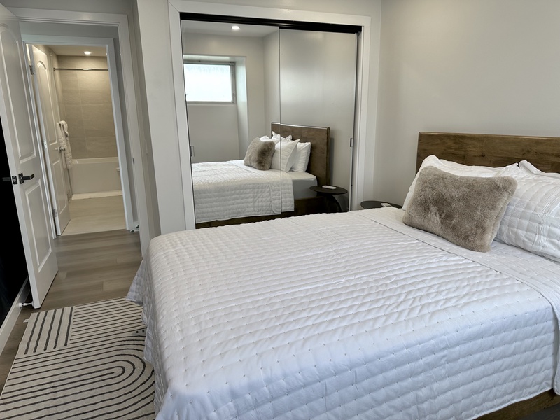 Bedroom with queen bed mirror closet doors and AC