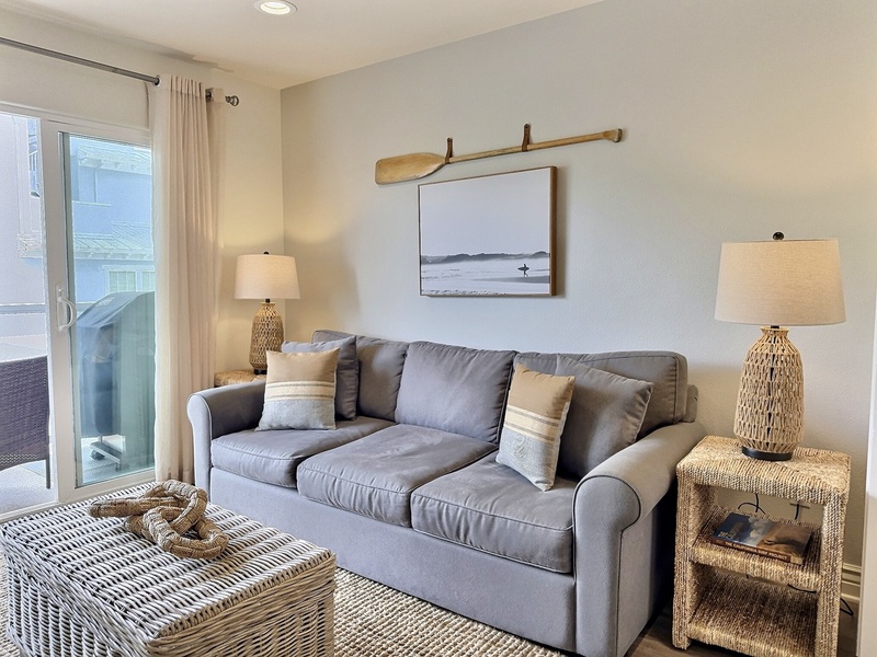 The sun-filled living room features large sliding doors that open to a private balcony with seating and a natural gas BBQ.