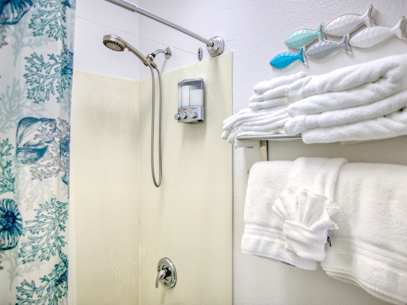 The bathroom includes a tub/shower combination, plush white towels, and complimentary bath soaps for a refreshing start or relaxing end to your day.