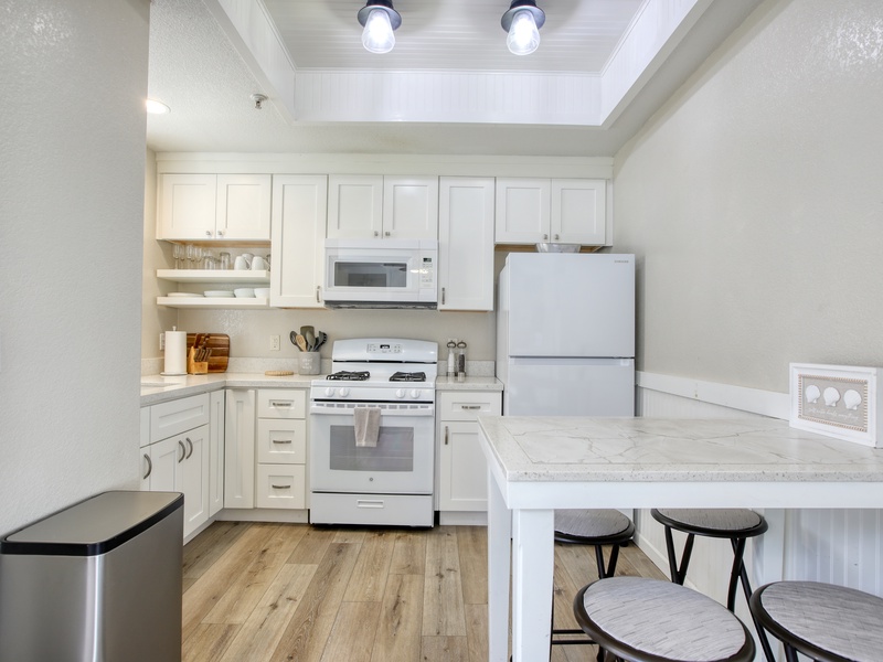 Fully equipped kitchen with everything you need to cook and serve, plus dining for four — perfect for sharing meals after a day at the beach.